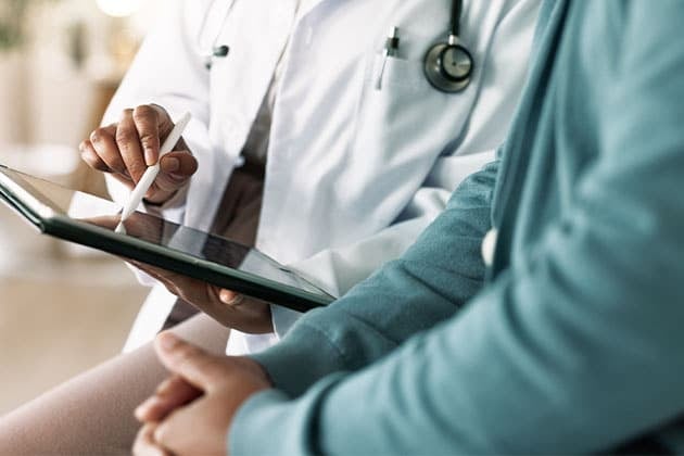 Doctor with patient explaining health results on tablet